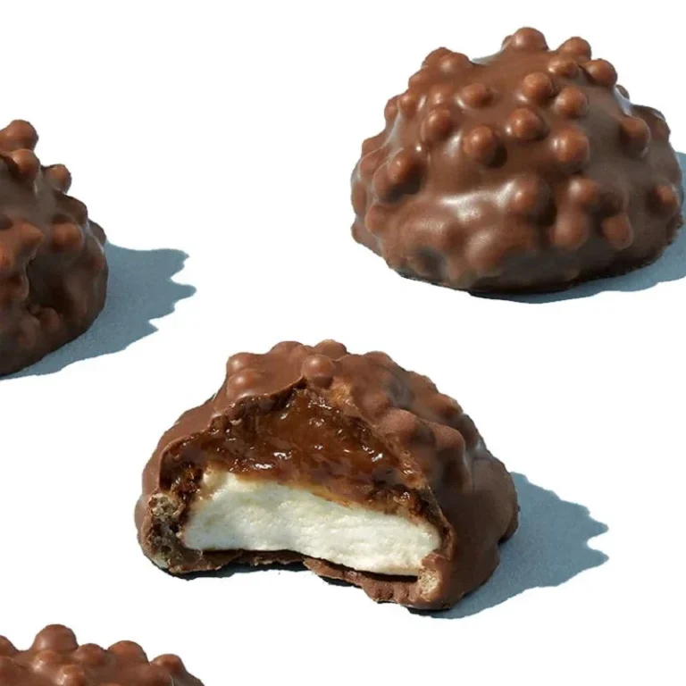 Bonbons en chocolat avec une garniture crémeuse et croustillante, dont l'un est coupé.