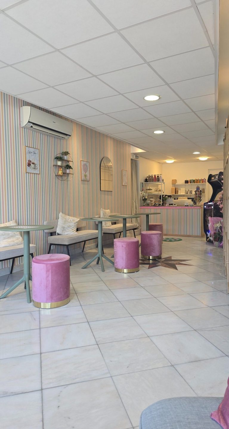 Intérieur d'un café avec des tables et des tabourets roses, atmosphère chaleureuse.