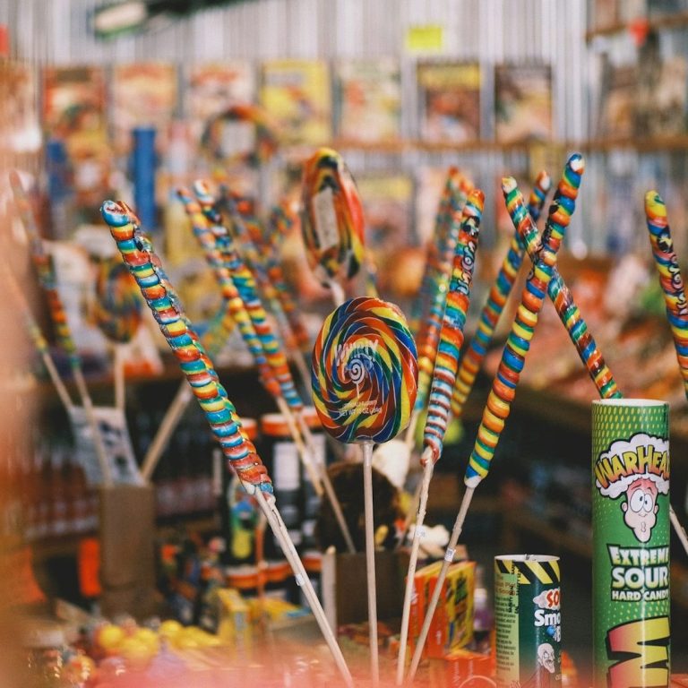 Des bonbons colorés en vrac, incluant des sucettes en spirale et des bâtons arc-en-ciel.