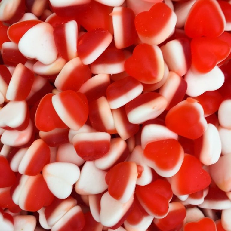 Bonbons en forme de cœurs rouges et blancs, dispersés sur une surface.